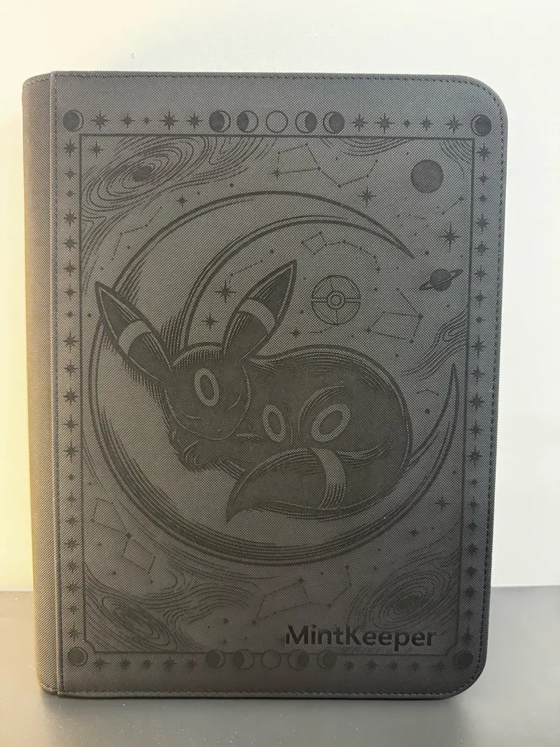 Black binder engraved in gold with a crescent moon, an Umbreon-inspired figure curled inside it, moon phases, stars, and the title Crescent Dreams.